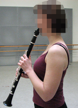 Henkilö soittaa klarinettia sivustapäin katsottuna.