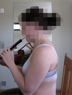 Henkilö soittaa oboeta istuen sivusta päin katsottuna.