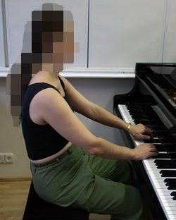 Henkilö soittaa pianoa sivusta päin katsottuna.