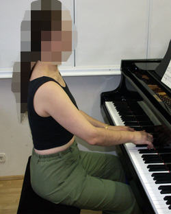 Henkilö soittaa pianoa sivusta päin katsottuna.